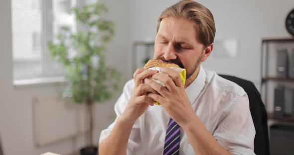 Bearded Man Enjoying Burger at Work