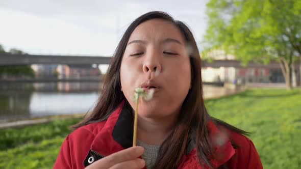 Front view of Asian woman blowing pollen at the park on the weekend