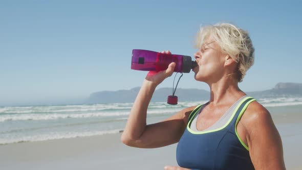 Athletic woman drinking water on the beach