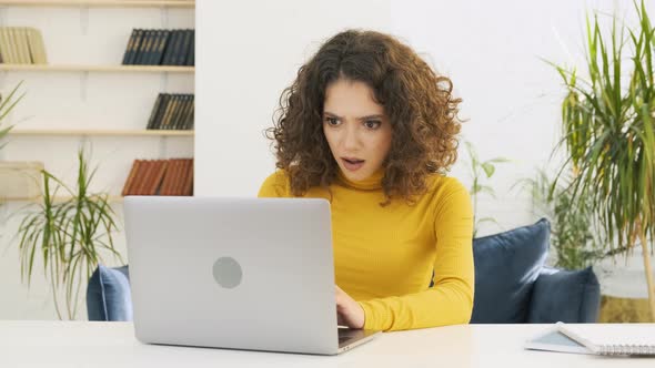 Young Pretty Woman Sitting at the Table at Home Working Using Computer Laptop Afraid and Shocked