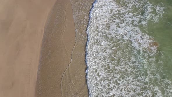 Aerial View of Person Walking Along Coast with Water Rushing in