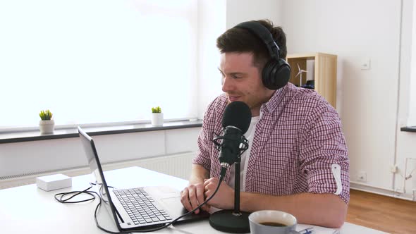 Man in Headphones with Laptop Speaks To Microphone 