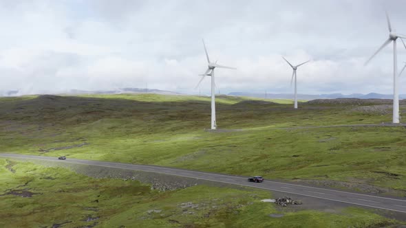 Drone Flight Over Landscape With Cars Driving Along Road By Wind Turbines