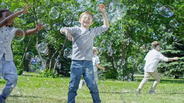 Kids Chasing Bubbles on Green Lawn in Park alt