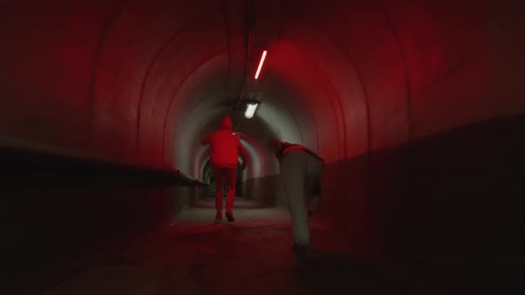 Parkourists Freerunning in Dark Tunnel