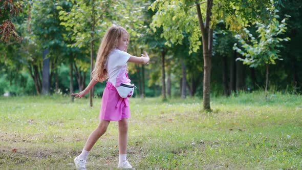 Girl having fun in park. Fashion little girl dancing in green park