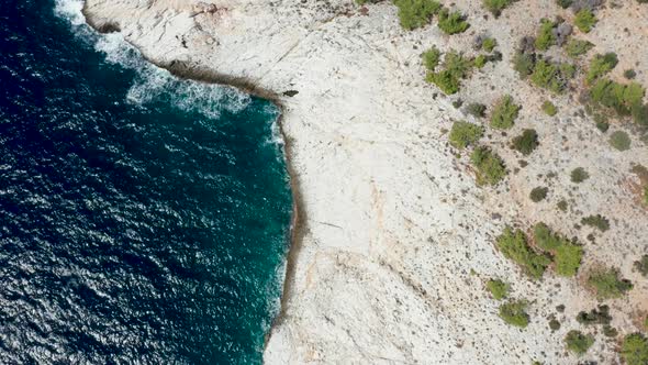 Drone Flying Along Rocky Coast Line and Dreep Blue Sea Water