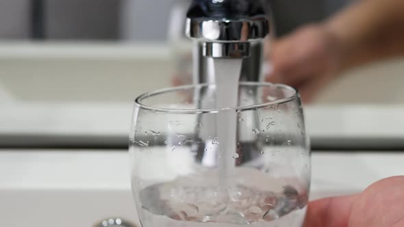 Man Hand Holding A Glass Pour Filtered Drinking Water. The Person Consumes Water.  Tap Water.