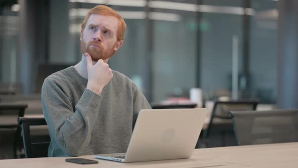 Young Man Thinking While Working on Laptop in Office