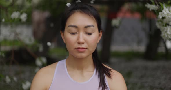 Woman Doing Yoga Pose on the Background of a Blooming Apple Tree