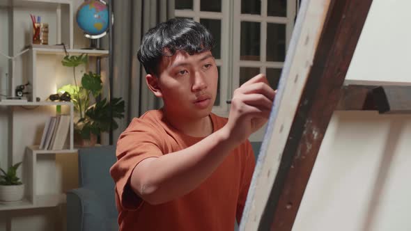 Asian Artist Boy Holding Paintbrush Mixed Colour And Painting On The Canvas