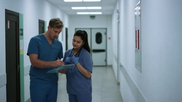 Two Physicians Hurrying Help Patients After Conversation in Clinic Corridor