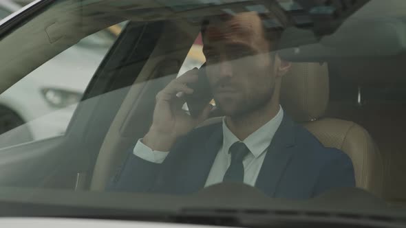 Businessman Talking on Phone in Front Car Seat