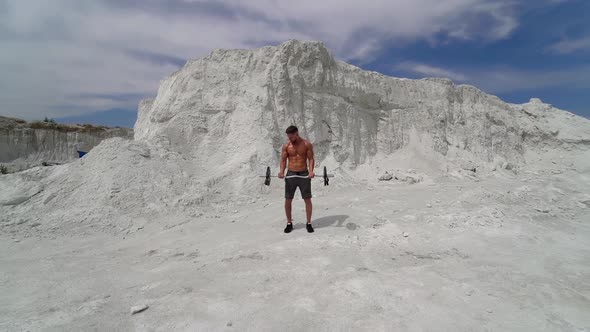 Bodybuilder is doing his workout in amazing white mountains.