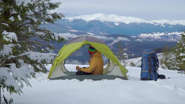 Tourist Relaxes in a Tent in the Mountains in Winter