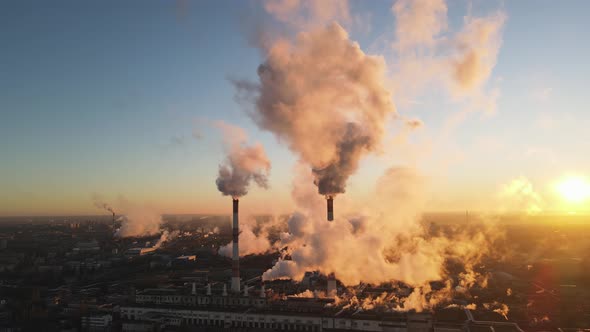 Factory chimneys producing smoke at sunrise, aerial view