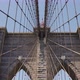 The Brooklyn Bridge with an American Flag on the top during a sunny day with blue skies, tilt shot. - VideoHive Item for Sale