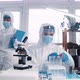 Focused Young Female Lab Scientist Doctor in Full Medical Protection Suit and Shield Works on New - VideoHive Item for Sale