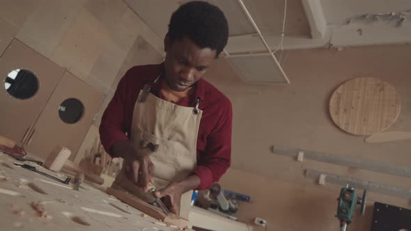 African-American Joiner Carving Wooden Board in Workshop