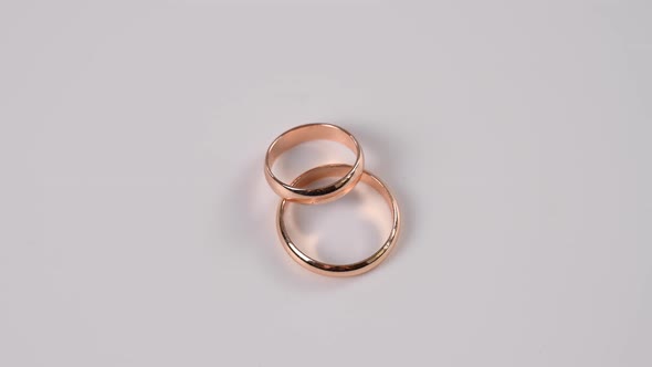 Two Wedding Rings Spin on a White Background