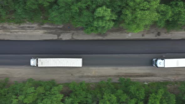 Aerial Shot of White Trucks Driving on New Freeway Running Through Forest