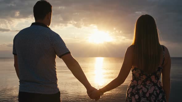 Couple Holding Hands at Sunset on the Sea Background