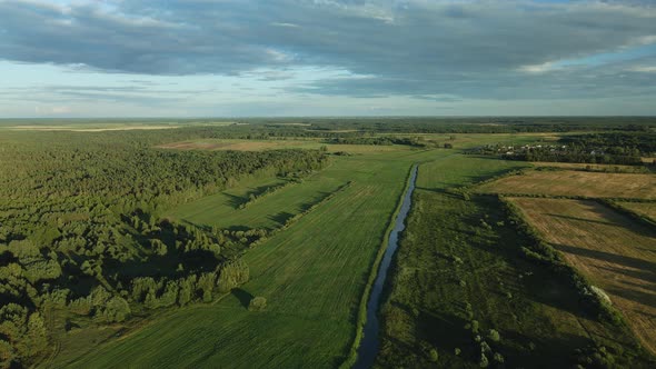 Flight Over The River In The Valley. A Village In The Middle Of The Forest Is Visible In The Distanc