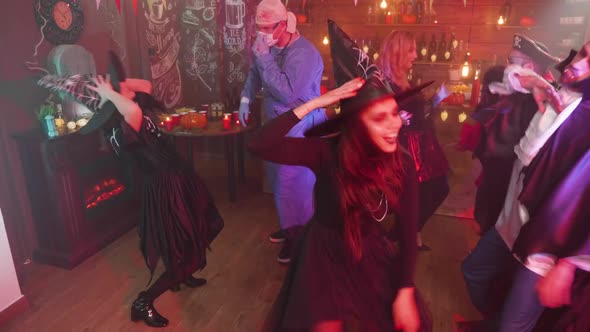 Woman in Evil Witch Costume Dancing in the Middle of a Group of Friends Celebrating Halloween