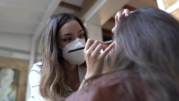 Make-up artist wearing protective mask, applying make-up for wedding