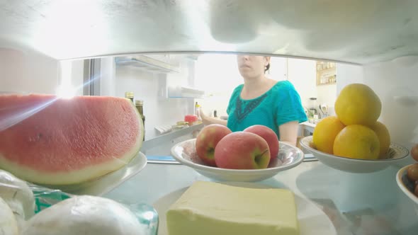 POV shot inside a refrigerator of woman opening the door and taking out food