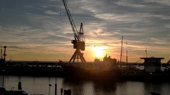 Dolly shot of a sun set in the harbour of Harlingen. Tug boat Holland and a vintage crane, backlight