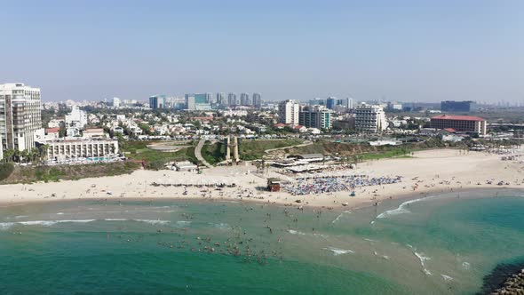 Large groups of tourists and locals enjoy the wonderful summer weather on the beach and in the Medit