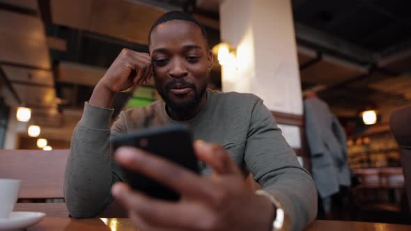 African American Man Online Chatting in a Cafe