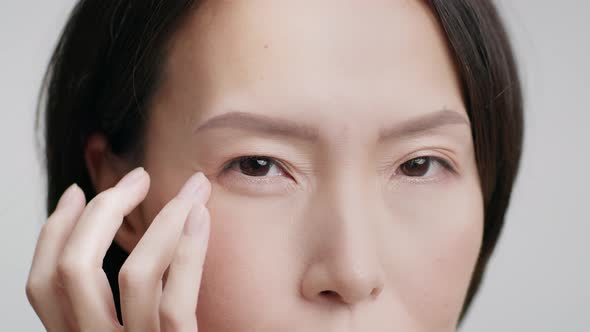 Closeup Of Middle Aged Japanese Woman Touching Wrinkles Gray Background