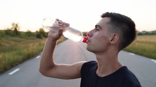 Profile Portrait of Handsome Sportsman Drinking a Bottle of Water and Smiling