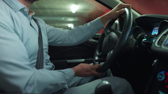 Man Driving Car Through an Underground Parking Lot and is Looking for a Place to Park or Drives Away