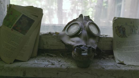 Old decaying gas mask and books left in Pripyat after the Chernobyl nuclear disaster. Close up, boom