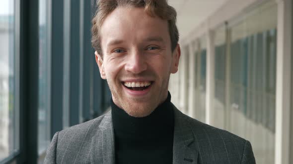 Close up portrait of handsome businessman smiling cheerfully to the camera. In formal wear standing