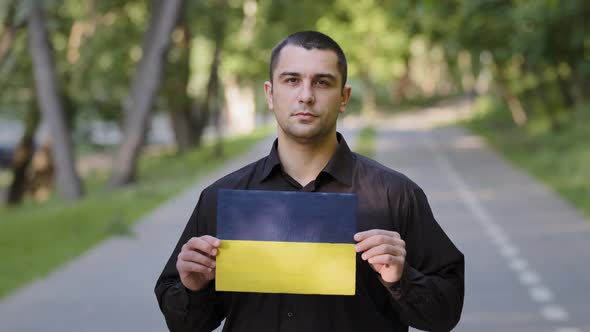 Serious Man Caucasian Adult Patriot Activist Protester Wear Black Shirt Stand Outside in Park Hold