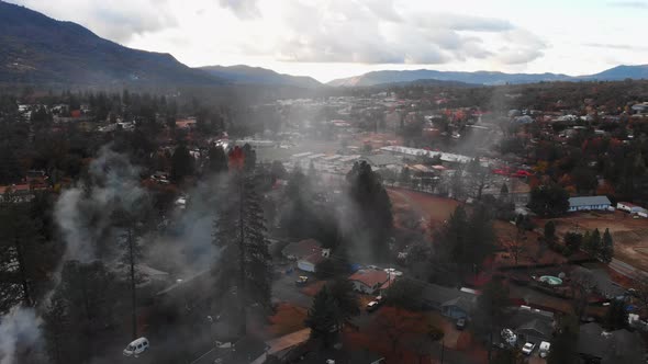 Aerial view of chimney smoke over a mountain neighborhood during winter time