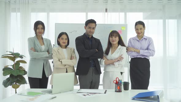 Portrait of a group of smiling Asian business people meeting, discuss documents,