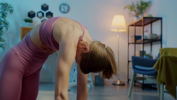 Portrait of Young Lady Doing Yoga Enjoying Practice Stretching Spine Indoors at Night at Home