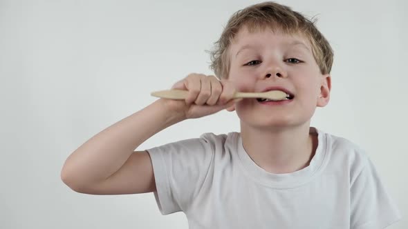 Young Little Boy Brushing His Teeth Using Bamboo Tooth Brush for Cleaning Teeth on White Background