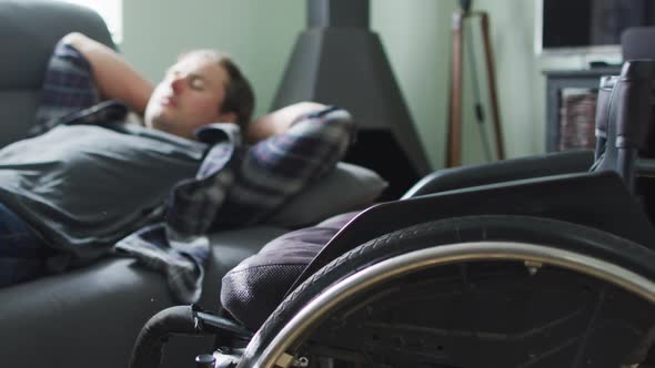 Relaxed caucasian disabled man lying on sofa in living room