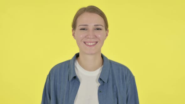 Young Woman Smiling at Camera on Yellow Background