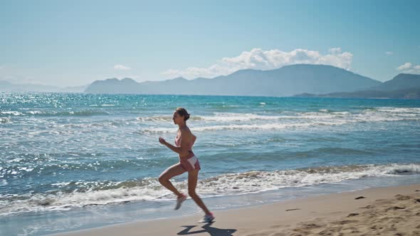 Strong Young Woman Running on Stormy Beach Sprinting Fast Exercising Cardio Workout Training Focused