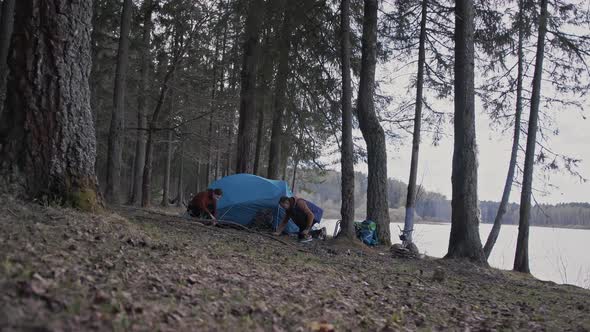 A Couple of Lovers are Setting Up a Tent Throwing a Canopy Over the Tent