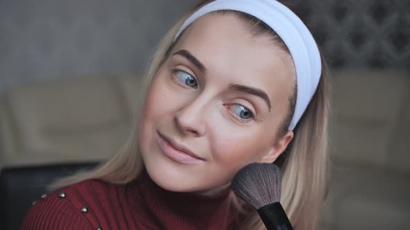 Blonde Applying Facial Powder to Herself with a Brush