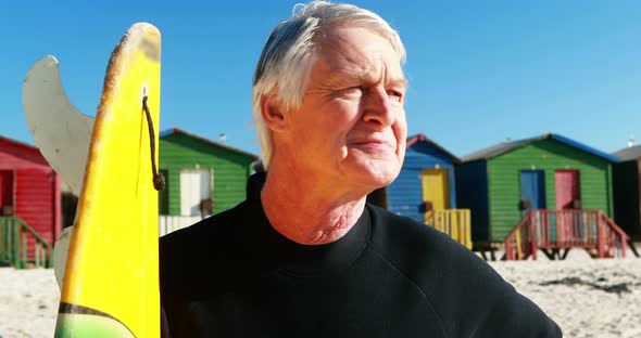 Senior man with surfboard standing on beach