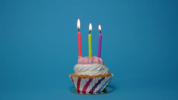 Birthday Cupcake with Lit Candle on Blue Background